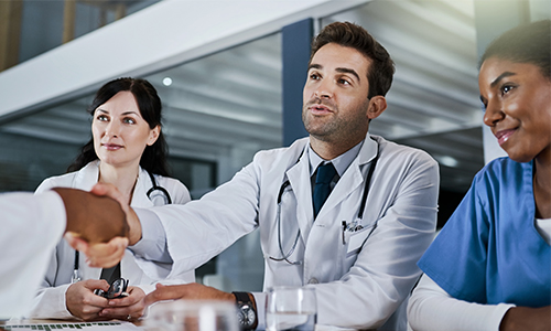 Three healthcare workers meeting another healthcare worker